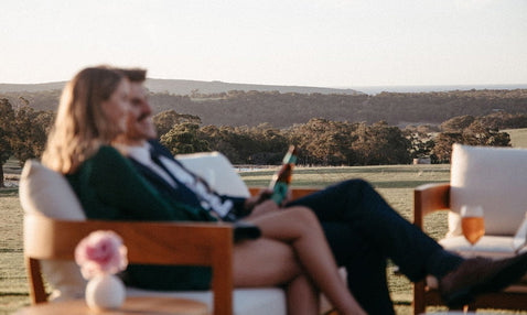 A couple sitting on an outdoor chair during a wedding at Eagle Bay Brewing Co laughing.